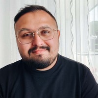 Ilia Vasilev, ein Mann mit kurzen schwarzen Haaren, Bart und Brille, lächelt in die Kamera.