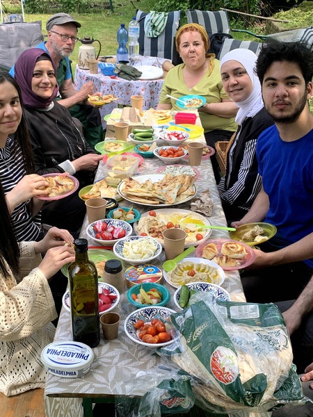 Mehrere Menschen sitzen beim Picknick im gemeinsamen Garten