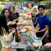 Mehrere Menschen sitzen beim Picknick im gemeinsamen Garten