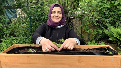 Ferial Al Kwifi steht an einem Hochbeet im Garten