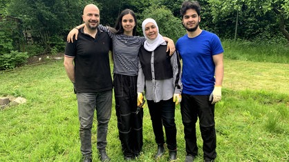 Die Architekten Salah Alhalabi und Heba Hussein stehen mit ihren Kindern im Garten