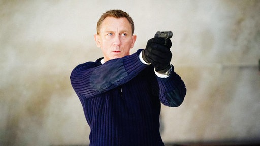 Daniel Craig als James Bond, er zielt mit einer Pistole an der Kamera vorbei