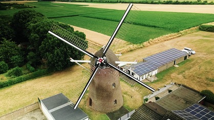 Vor einem Getreidefeld steht die historische Windmühle von Kirchhoven.