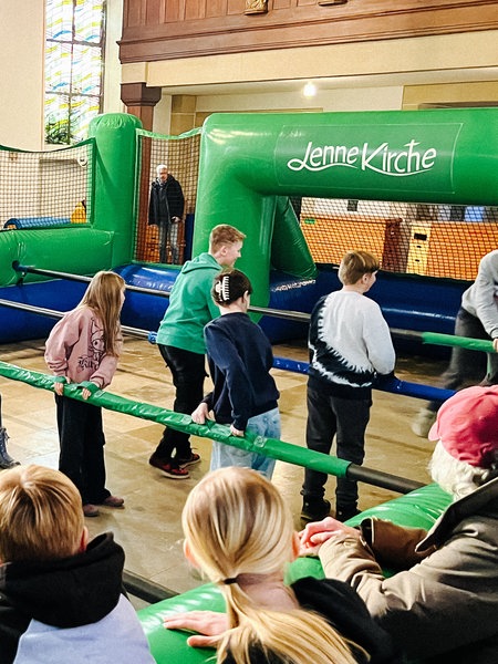Kinder spielen in einem Menschenkicker in einer Kirche.