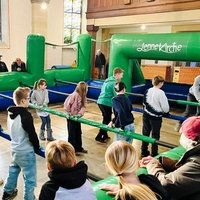 Kinder spielen in einem Menschenkicker in einer Kirche.