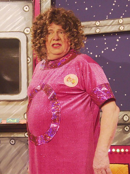 Alexander Moll steht in pinker Kleidung und mit Perücke auf der Bühne im Theater Filmdose in Köln