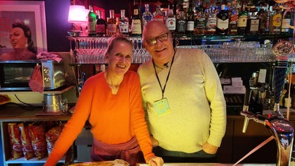 Heike und Alexander Moll stehen hinter der Theke im Theater "Filmdose", im Hintergrund ein Regal mit Flaschen und Gläsern