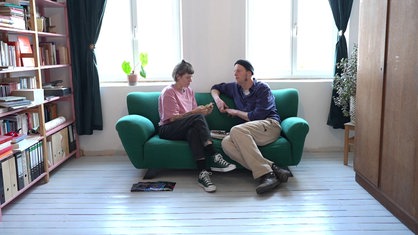 Katrin und Lukas Mokros sitzen auf einem grünen Sofa
