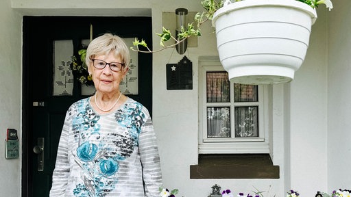 Eine Frau steht im Eingang ihres Hauses