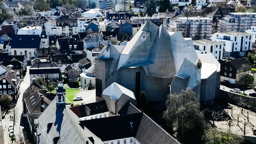 Luftaufnahme von rundlichem Kirchengebäude aus Sichtbeton, mit unterschiedlich eckigen Erhebungen