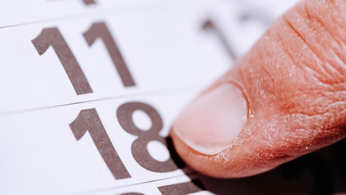 Ein Finger zeigt auf die Zahl 18 in einem Kalender.