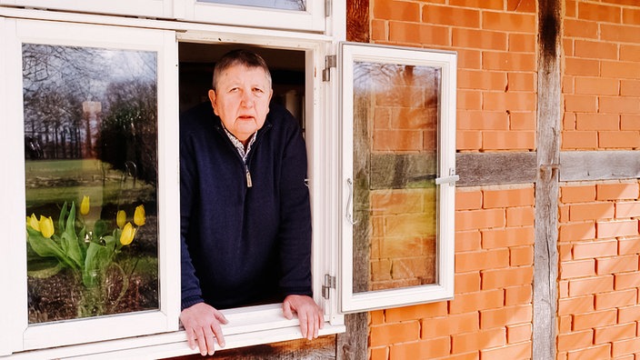 Eine Frau lehnt sich aus einem Fenster und blickt suchend hinaus
