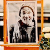 Ein Schwarz-Weiß-Foto in einem Rahmen, das Olli zeigt. Davor stehen weiße Rosen.