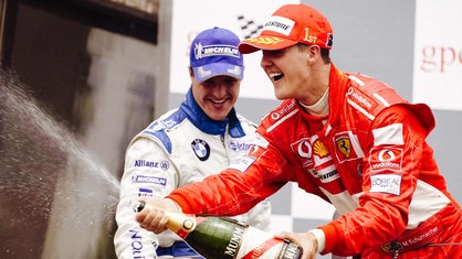 Michael Schumacher feiert im roten Ferrari-Rennanzug nach einem gewonnen Rennen