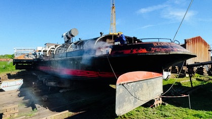 Die "Oscar Huber" in der Werft von vorne rechts. Auf dem Deck kärchert ein Mitarbeiter die Oberflächen.