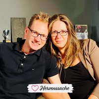 Simone und Daniel lächeln nebeneinander in die Kamera.