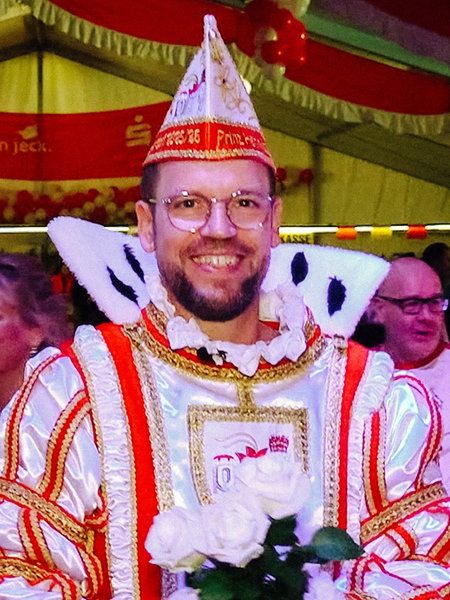 Henning Bargmann steht in seinem Prinzen-Ornat im Festzelt und grinst.