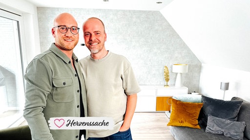 Dennis und Danny lächeln in ihrem Zuhause.