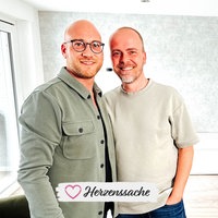 Dennis und Danny lächeln in ihrem Zuhause.