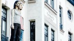 Die Skulptur eines Paares steht auf einer Litfaßsäule.