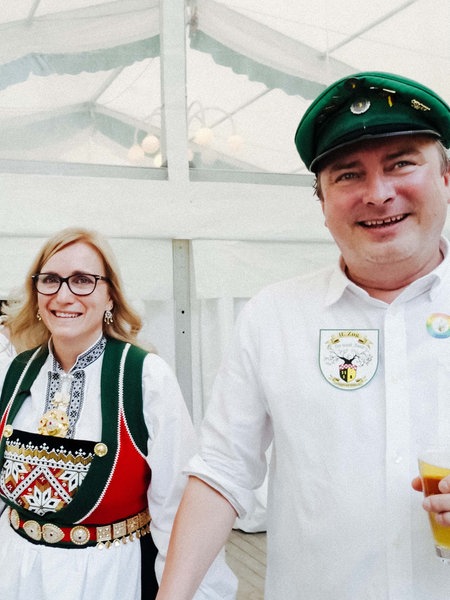 Ana und Sascha Radermacher in ihren Schützenfest-Trachten. Sascha hält ein Glas Bier in der linken Hand.