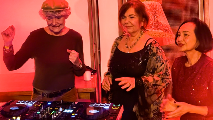 Drei Frauen stehen vor einem DJ-Pult.