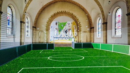 Ein Fußballfeld ist in einer Kirche aufgebaut, im Hintergrund befindet sich der Altarraum.