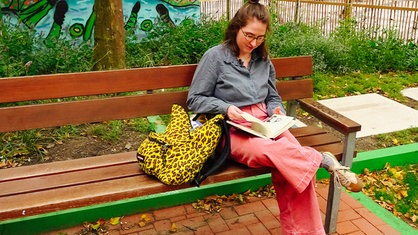 Ika Sperling sitzt auf einer Bank in der Dortmunder Innenstadt und schaut in ihr Skizzenbuch.