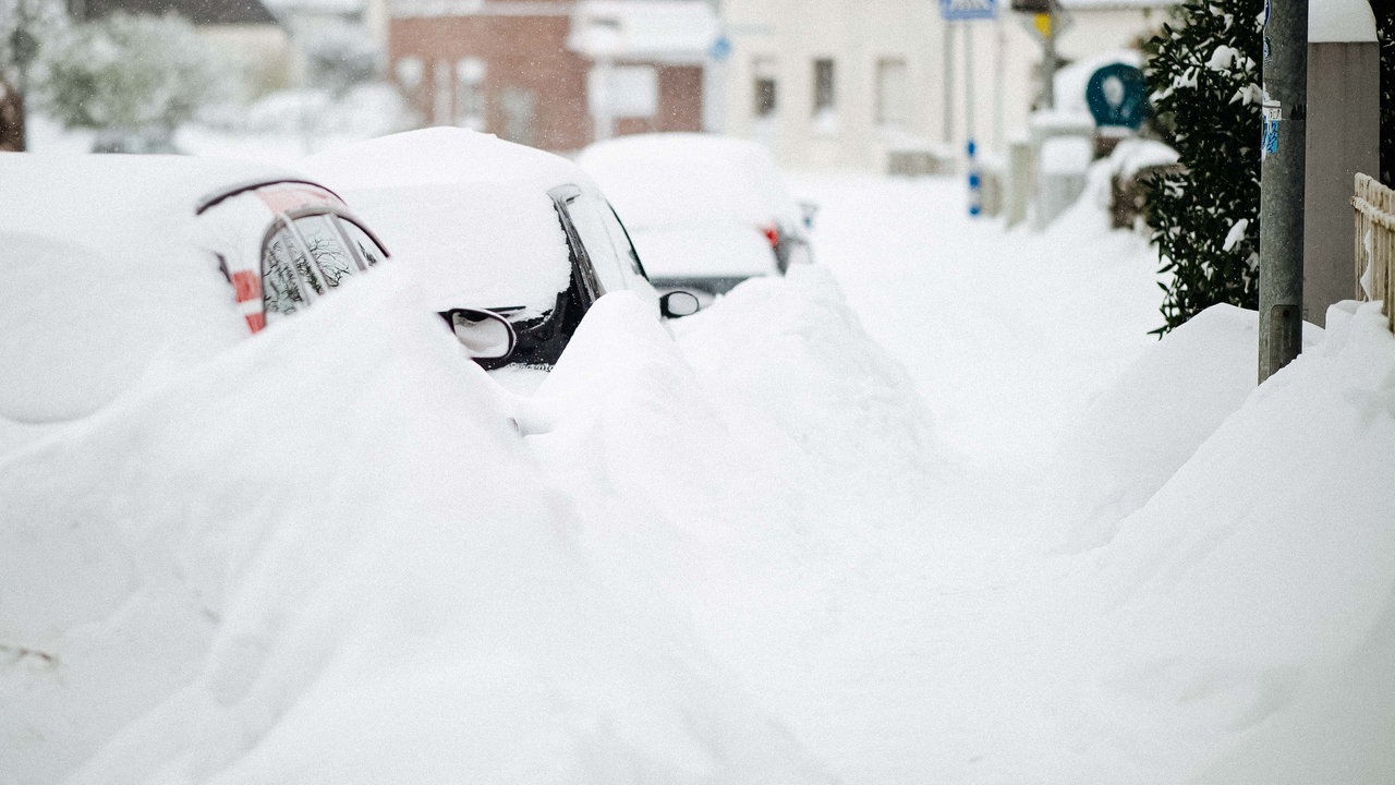 Drei Autos am Straßenrand. Sie sind unter einer dicken Schneeschicht kaum zu erkennen.