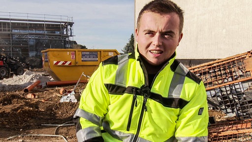 Niklas Zartenar auf der Baustelle. Er trägt neongelbe Arbeitskleidung.