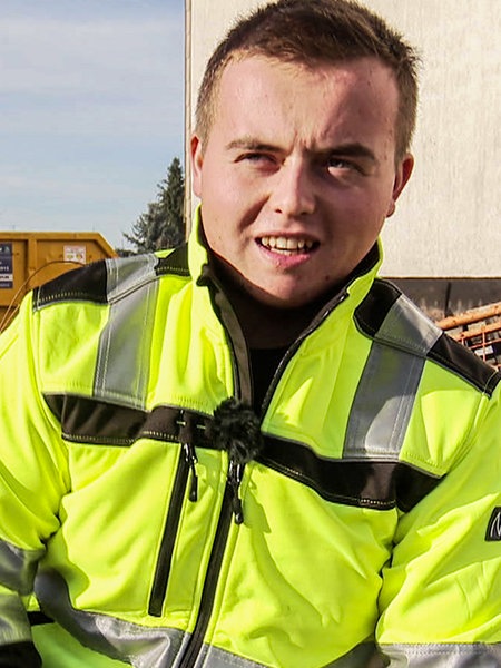 Niklas Zartenar auf der Baustelle. Er trägt neongelbe Arbeitskleidung.