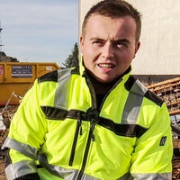 Niklas Zartenar auf der Baustelle. Er trägt neongelbe Arbeitskleidung.