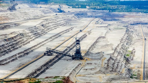 Ein Loch aus abgegrabenem Boden, in dem drei Braunkohle-Bagger stehen