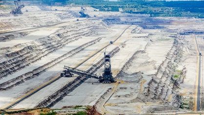 Ein Loch aus abgegrabenem Boden, in dem drei Braunkohle-Bagger stehen