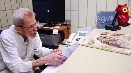 Diethelm Graf von Plettenberg sitzt an einem Schreibtisch und blättert in Unterlagen.
