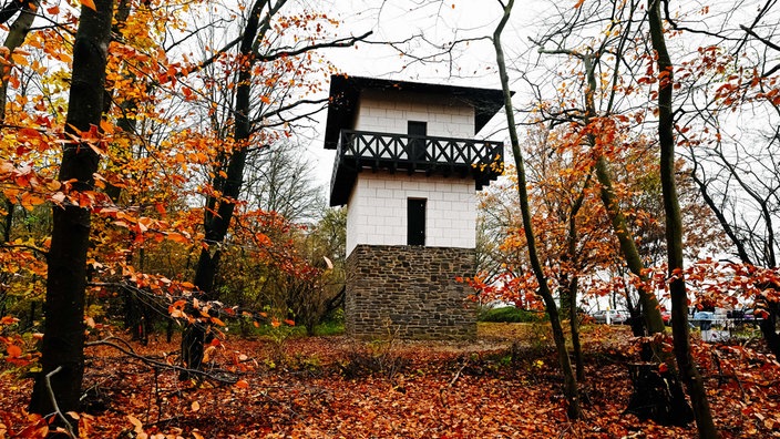 Ein weiß-brauner nachgebauter Wachturm in einem Wald bei Neuss
