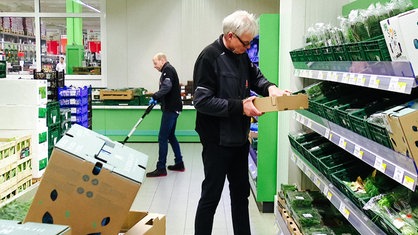 Frank Harmann sortiert Kräuter in einem Regal ein, neben ihm stapeln sich Kisten