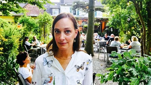 Die Wirtin Julia Söhngen steht in dem Biergarten ihrer Kneipe "Kastanie am Hax"