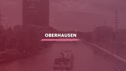 Der Blick von oben auf den Rhein-Herne-Kanal mit einer Fähre, die gerade Oberhausen durchquert. Darauf der Schriftzug "Oberhausen".