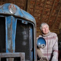 Marianne Lütkehölter steht in ihrer Scheune in Bielefeld neben einem alten blauen Traktor.