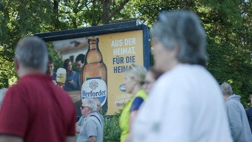 Demonstranten vor Werbetafel der Brauerei