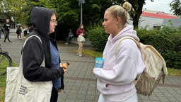Zwei Schülerin des Berufskollegs stehen sich gegenüber und sprechen miteinander. 