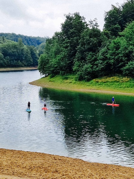 Auf einer Talsperre machen drei Frauen Standup-Paddling.