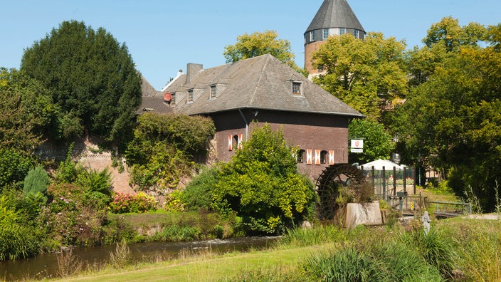 Die "Brüggener Mühle", eine Wassermühle am Unterlauf der Schwalm. Dahinter ein Burgtur.