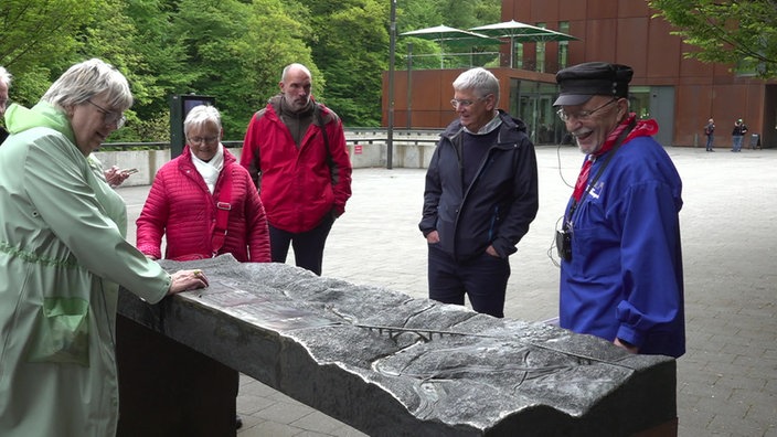 Mehrere Menschen stehen vor einer Abbildung des Brückenparks Müngsten