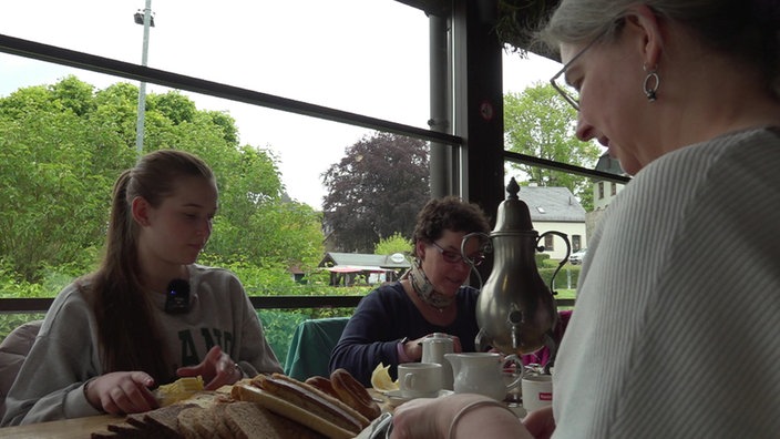 Mehrere Menschen sitzen an großer Kaffeetafel