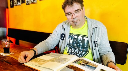 Axel Manns betrachtet ein Fotoalbum in einem Café