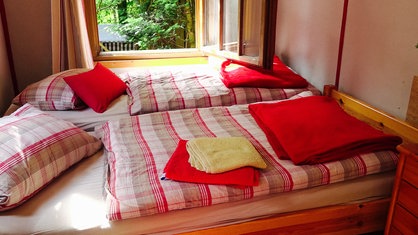 Das Doppelbett in dem alten Bauwagen mit ordentlich gefalteter Bettwäsche.