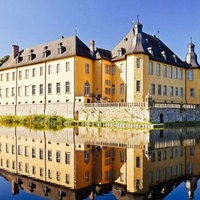 Ein gelbes Schloss. Es ist umgeben von Wasser.