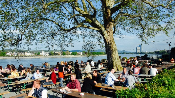 Menschen sitzen im Biergarten "Am alten Zoll"